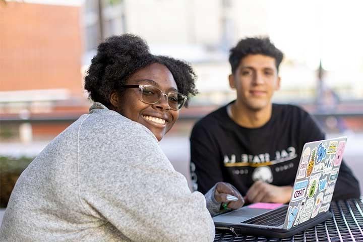两个学生微笑着用笔记本电脑学习